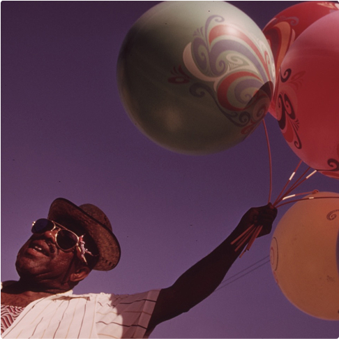 photograph of man holding balloons